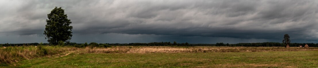 Dramatic view of a shelf cloud over a field, horizontal cloud formation, panorama view.