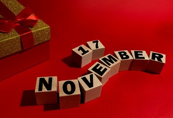 November 17 on wooden cubes ,red gift box on a red background.Autumn .Calendar for November.