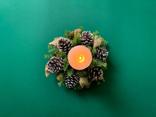 Obraz na płótnie Canvas Flat lay of Christmas wreath with pine branches and candle on green background.