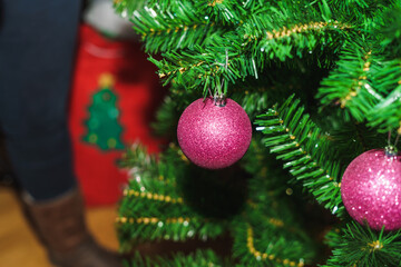 Purple Christmas ball hanging in the tree with a christmas sock in the background