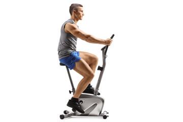 Profile shot of a fit young man in sportswear riding a stationary bike