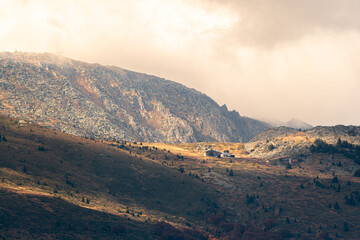 Autumn landscape in the mountains cloudy day sunrays wooden cottage on a ridge warm beautiful nature