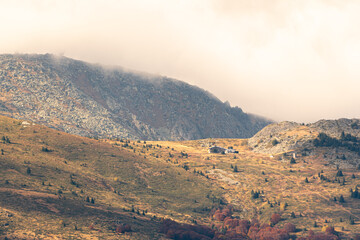Autumn landscape in the mountains cloudy day sunrays wooden cottage on a ridge warm beautiful nature