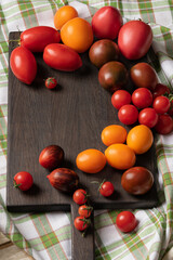 top view of tomatoes of different varieties. Harvest of the nightshade family on dark cutting board
