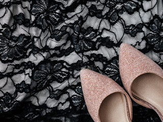 Sexy fashion concept with women's clothes and accessories. Glittery pink shoes and lace black dress as background. Flat lay, top view. Minimal feminine vogue concept. Party time