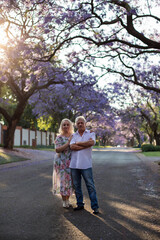 elderly man and woman walk down the street with blooming trees