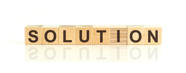 Wooden Blocks with the text: solution. The text is written in black letters and is reflected in the mirror surface of the table.