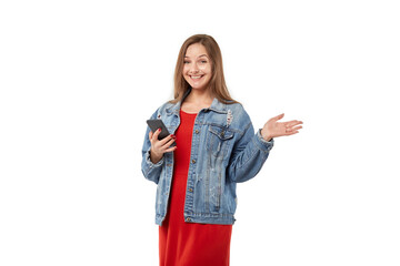 Obraz premium A young blonde woman smiles, looks at the camera and holds a mobile phone in her hand. White isolated background.