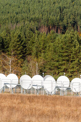 Satellite dish array communication base cell tower among autumn forest vibrant rural modern