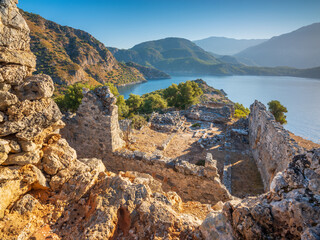 morning lights on walls of antique temple on turkish island Gemilie with sea and mountains view