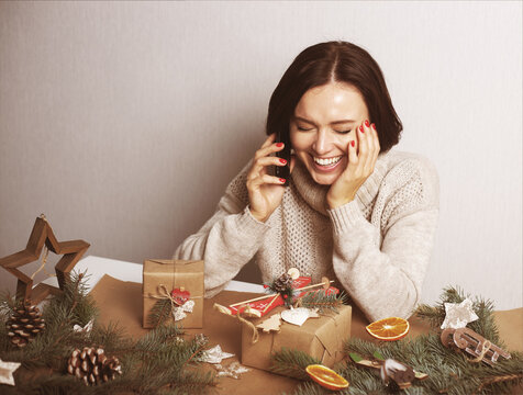 Happy young woman talking by smartphone and smiling among Christmas zero waste ornaments. Holiday social distansing. Online celebration in lockdown coronavirus quarantine new normal. Stay home.
