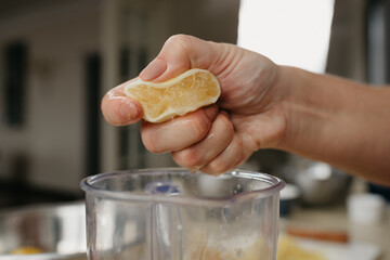 A close photo from the side of the hand of a woman who is crushing lemon juice by the hand into the...