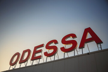 Fototapeta premium Odessa city name sign on the top of a sea port building with a blue sky at a background.