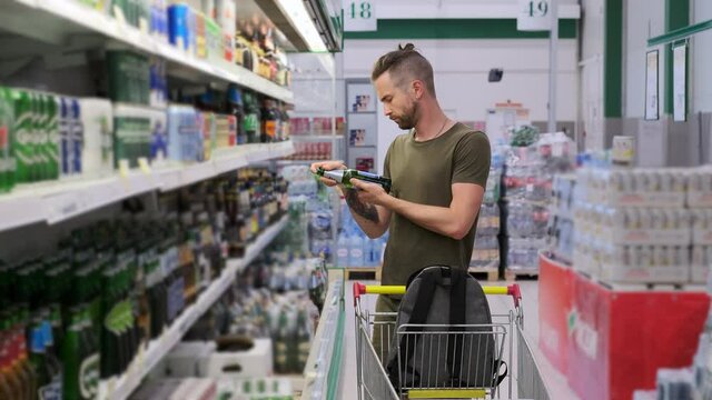 man is buying alcoholic and non-alcoholic beer in supermarket