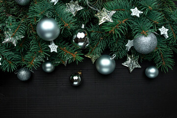 Fototapeta na wymiar Christmas tree branches with New Year's decor and stars on a dark wooden background.