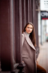 beautiful long-haired brunette in a light beige coat on the streets of the old city
