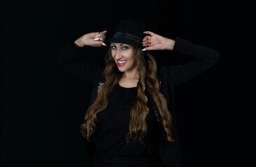 Fototapeta premium Woman in black hat on black background smiling. 