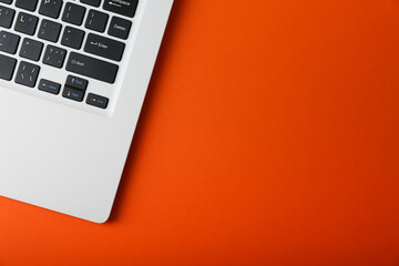 part of white laptop on orange background top view with copy space