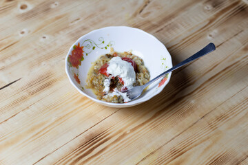 Stuffed stewed paprika with sour cream in white bowl, fork on wooden background