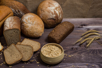 Assortment of bread, ears and grains of wheat on wooden table