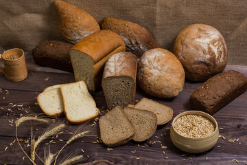 Assortment of bread, ears and grains of wheat on wooden table
