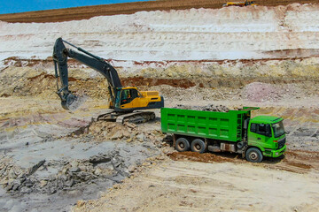 Clay mining. excavator  mines blue clay and loads into green truck.