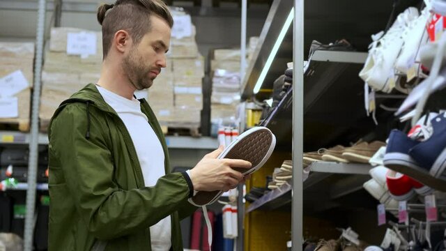 Man is going to buy white canvas shoes in the hypermarket