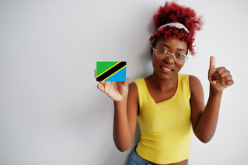 African woman with afro hair, wear yellow singlet and eyeglasses, hold Tanzania flag isolated on white background, show thumb up.