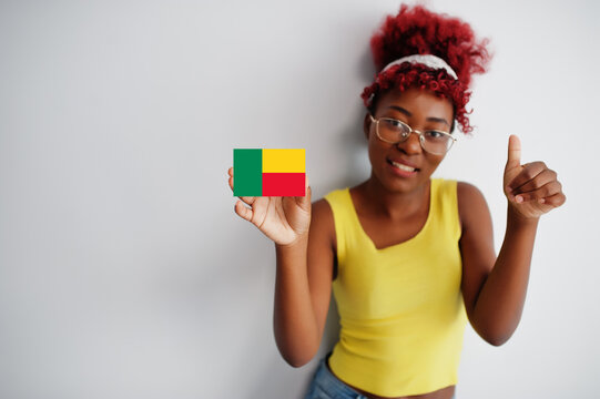 African woman with afro hair, wear yellow singlet and eyeglasses, hold Benin flag isolated on white background, show thumb up.