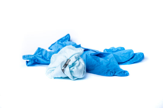 used surgical mask and blue latex surgical gloves on white background. the problem of disposal of medical waste and environmental pollution. End of quarantine. Covid-2019.