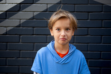 Funny portrait of a blonde caucasian boy whose hair rises and flies in the wind. Looks at the camera