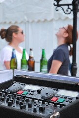 Close up of mixing desk with women laughing in the background