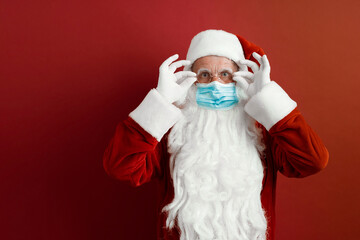 Santa Claus in a medical mask on a red background.