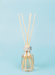 home fragrance in a glass diffuser with wooden sticks on a blue background