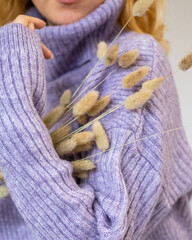Young beautiful woman in sweater holding bouquet in her hands 