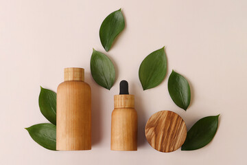 Creative layout from the wooden cosmetics containers with fresh green leafs around.Pretty pastel...