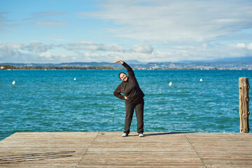 Active senior woman doing healthy exercises outdoors
