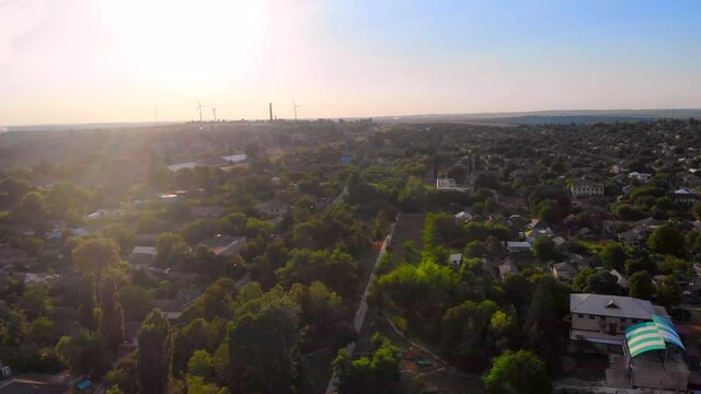 Aerial drone shot of Donduseni city with multiple residential buildings and greenery and fields. Sunset in Moldova