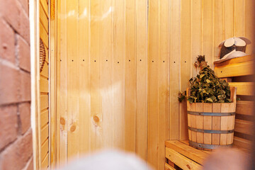 Interior details Finnish sauna steam room with traditional sauna accessories basin birch broom scoop felt hat towel. Traditional old Russian bathhouse SPA Concept. Relax country village bath concept.