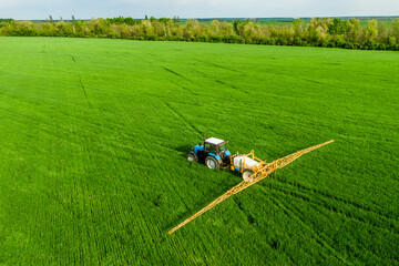 Tractor spray fertilizer on green field in spring drone high angle view, agriculture background concept.