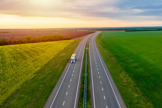 truck driving on asphalt road along the green fields. seen from the air. Aerial view landscape. drone photography.  cargo delivery