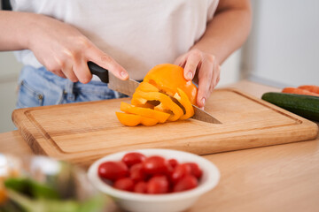 Woman chopping orange pepper