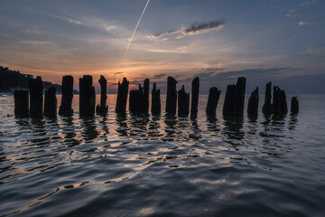 Sunset over wooden poles breakwater in Debki resort village on the Baltic Sea coast in Pomerania region of Poland