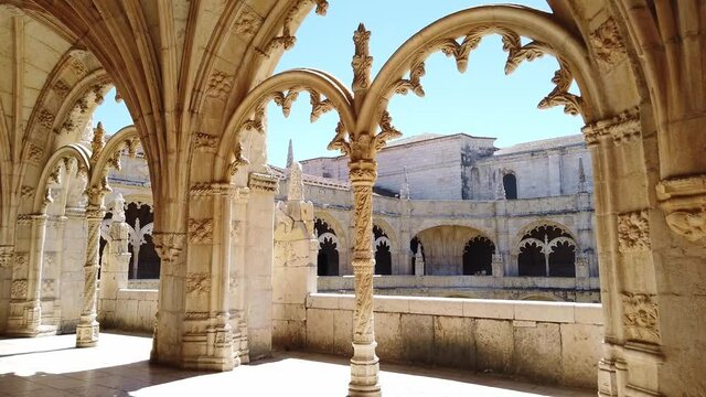 Walking on the upper level of the cloister and passing decorated arches with stone pillars in Jer&oacute;nimos Monastery