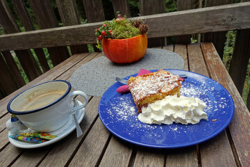 Pflaumenkuchen mit Sahne auf einem blauen Teller