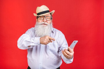 Old Senior shocked amazed Man dial phone number on smart phone, isolated on red background....