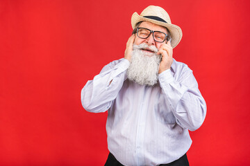 Old Senior Man dial phone number on smart phone, isolated on red background. Positive human emotion, facial expression. Using phone.
