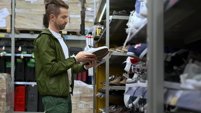 man is buying cheap shoes in hypermarket