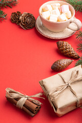 Christmas or New Year composition. Decorations, cones, fir and spruce branches, cup of coffee, on a red background. Side view, copy space.