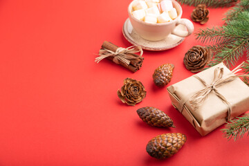 Christmas or New Year composition. Decorations, cones, fir and spruce branches, cup of coffee, on a red background. Side view, copy space.